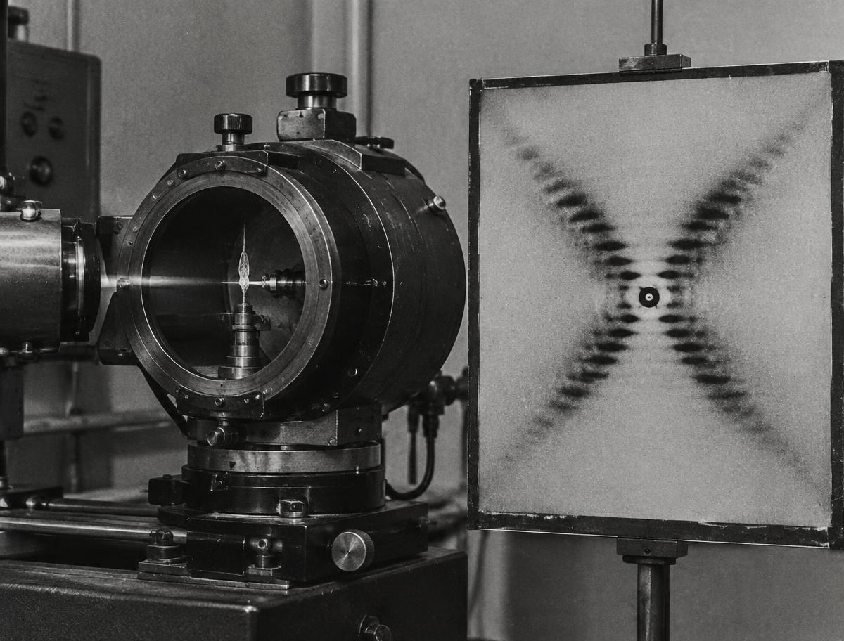 An X-ray crystallography camera and an X-shaped diffraction pattern, echoing Photo 51